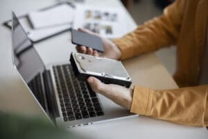 Person holding a hard drive that needs to be replaced with an SSD.